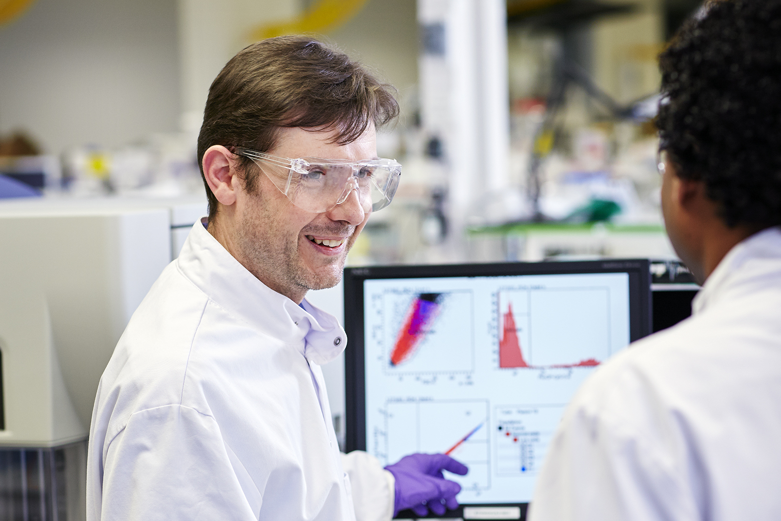 Man in lab pointing to results for a colleague