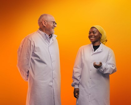 Two people in labcoats against an orange background