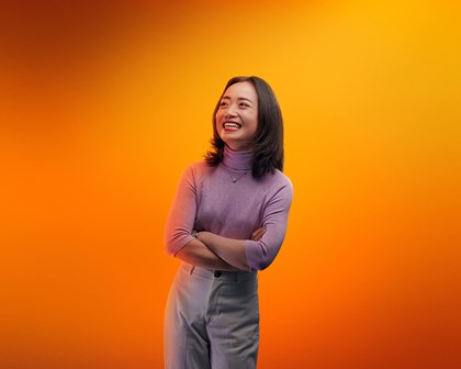 Woman smiling in front of an orange background.